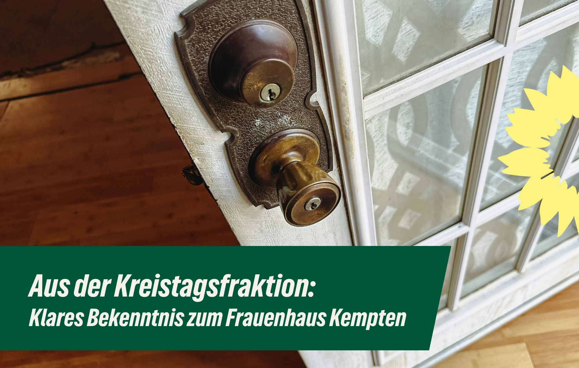 Alte Messingklinke mit Schloss an einer weißen Tür mit Glasfeld, darüber der Schriftzug „Aus der Kreistagsfraktion: Klares Bekenntnis zum Frauenhaus Kempten“.