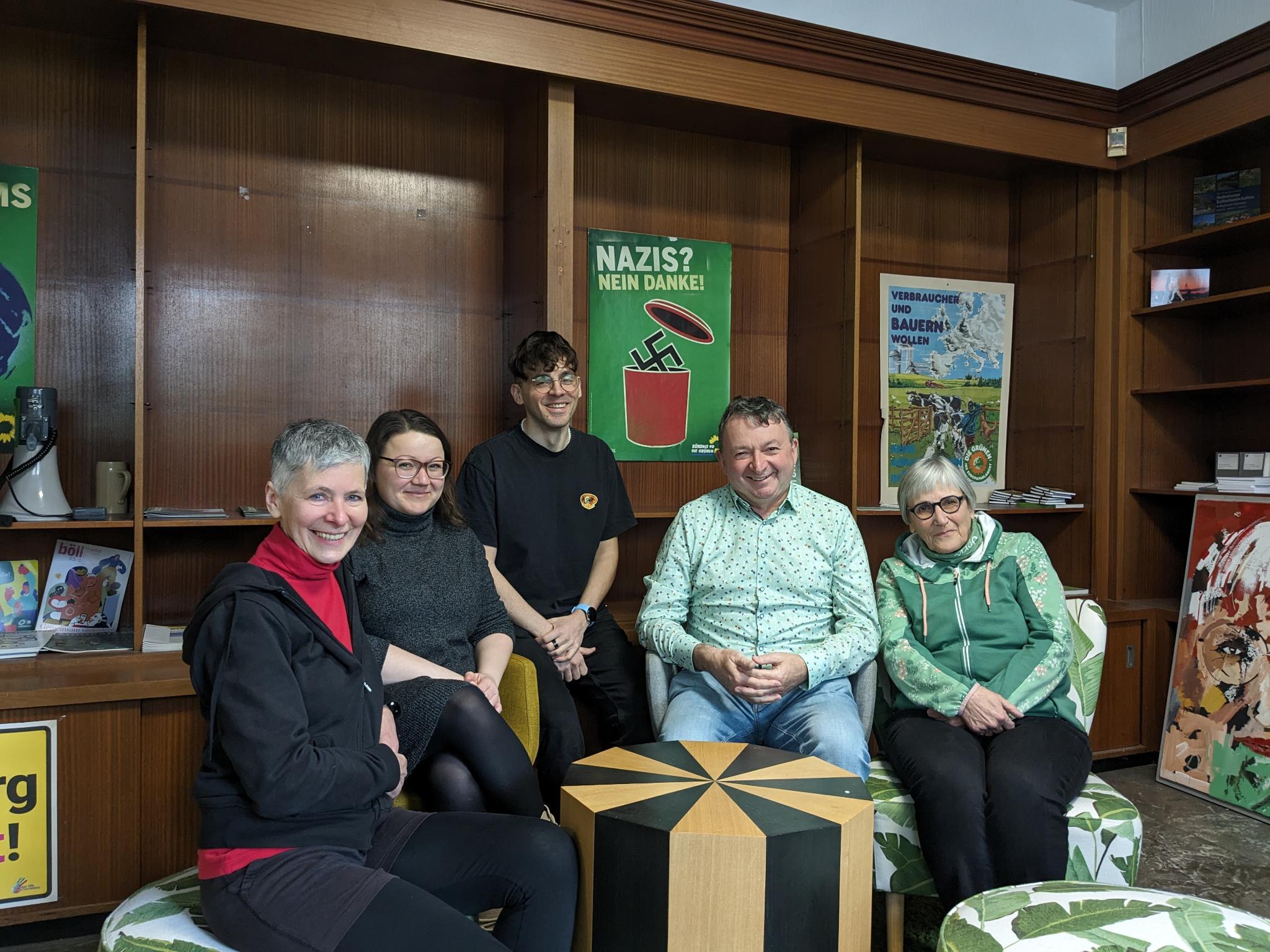 Bezirksvorstandsteam in Räumen der Augsburger Grünen vor einem Plakat "Nazis? Nein Danke!"